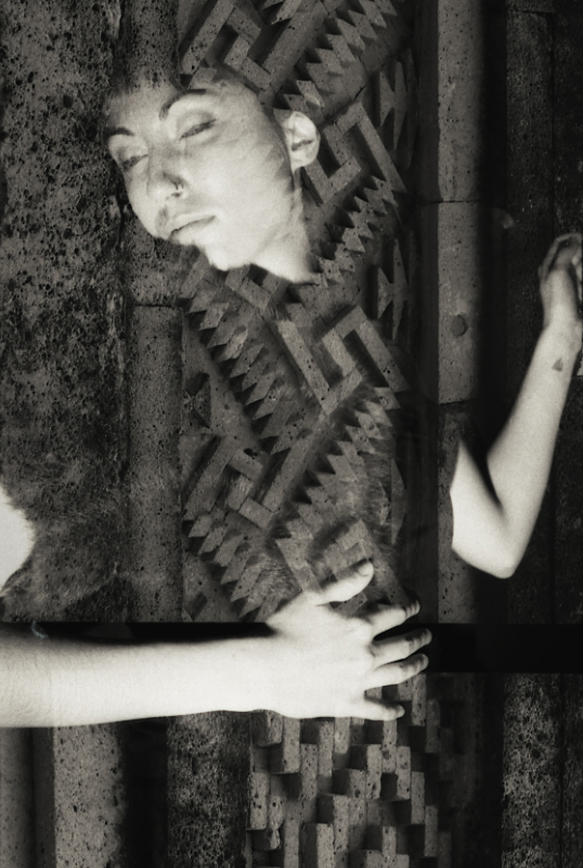 Black and white multiple exposure image of a person's body embedded within an ancient Mexican stone wall.