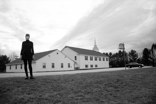 Jessica wearing all black, standing in front of an empty church building.