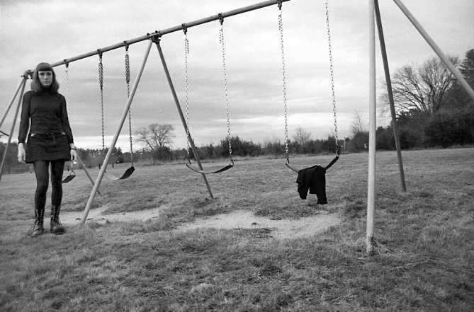 Jessica wearing all black, standing next to a swingset.