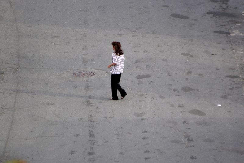 Color image of a woman crossing the road.