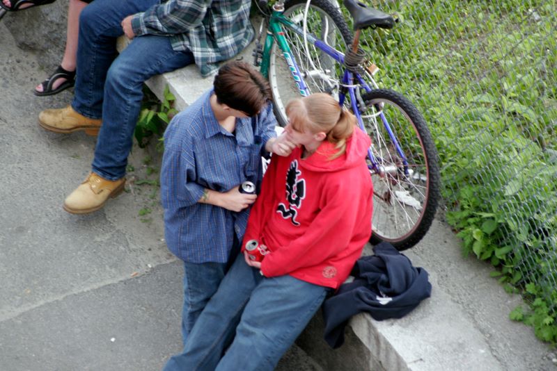 Color image of two people standing close looking at one another. One person is touching the other person's chin.